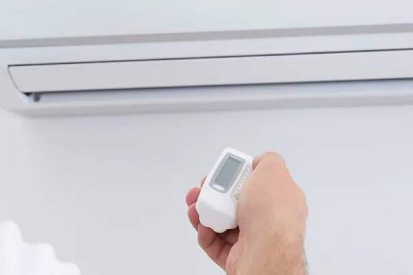 person turning on an air conditioner unit with a remote